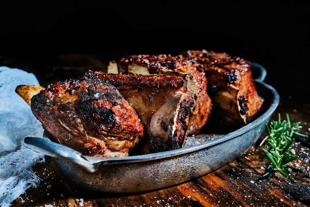 Mörrostade köttbitar med ben i en metallform, med rosmarin